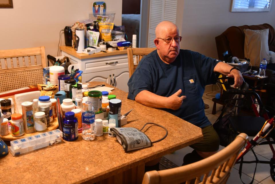 Daryl Wattenbarger, sitting at the dining room table with his wife, Kathy, checks his blood pressure. Daryl was in the hospital when he was offered a chance to participate in the Health First Hospital at Home program. The choice was obvious, he said: Stay in the hospital, or be at home with his dog and Kathy and her home-cooked meals. He was monitored by doctors and nurses in the teleremote monitoring program.