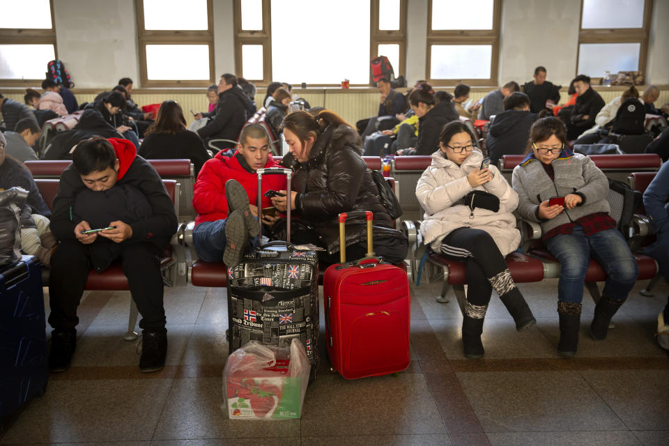 Travelers sit in waiting room at the Beijing Railway Station in Beijing, Friday, Jan. 17, 2020. As the Lunar New Year approached, Chinese travelers flocked to train stations and airports Friday to take part in a nationwide ritual: the world's biggest annual human migration. (AP Photo/Mark Schiefelbein)