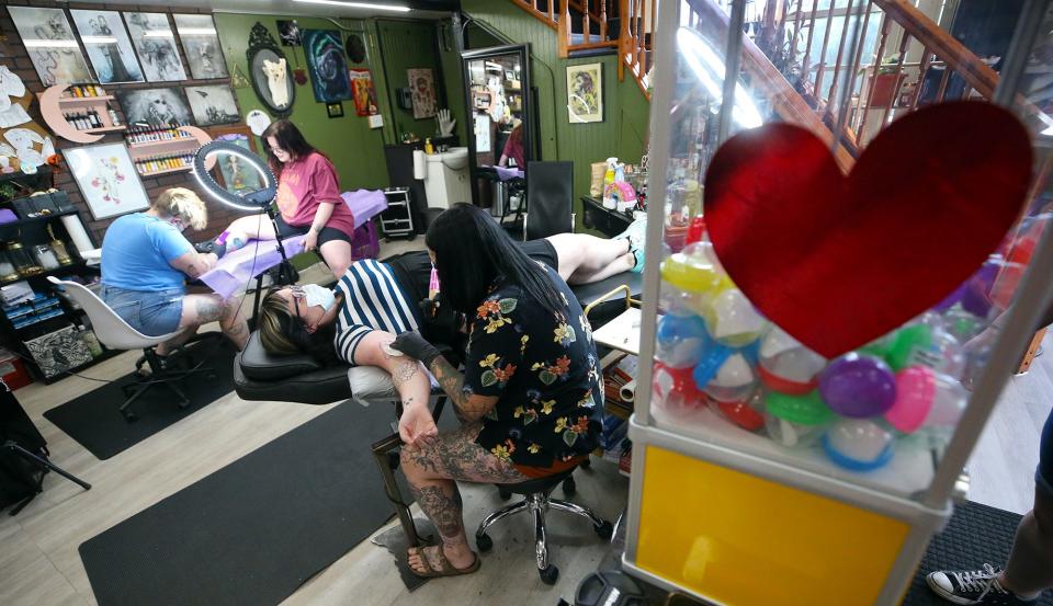 Black Amethyst Tattoo Co. artists Erica Rose, front, and Slinkii tattoo customers during the shop's flash sale to raise money for local abortion funds.