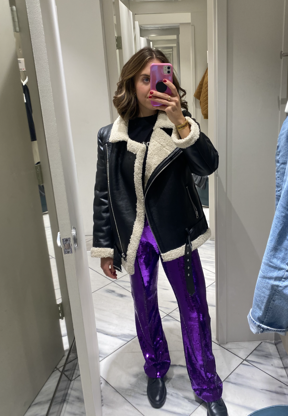 brunette woman wearing purple sequinned paco rabanne H&M pants and black and white aviator jacket 