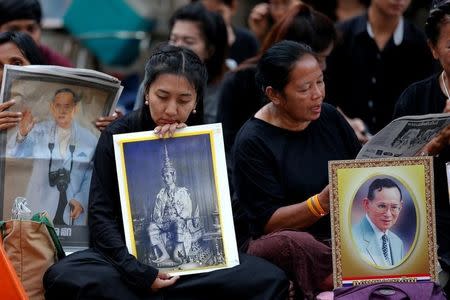 People hold portraits of Thailand's late King Bhumibol Adulyadej at the Siriraj hospital in Bangkok, Thailand, October 14, 2016. REUTERS/Chaiwat Subprasom