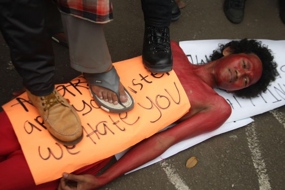 In this Monday, Sept 30, 2013 photo, protesters stamp on a man painted in red, representing "communism," lying on the street during an anti-communism protest outside the presidential palace in Jakarta, Indonesia. A new American-directed documentary, "The Act of Killing," challenges widely held views about hundreds of thousands of deaths carried out across Indonesia from 1965 to 1966 in the name of fighting communism. It explores the country's darkest open secret by allowing former mass killers to re-enact their horrors on screen. (AP Photo/Jakarta Globe, Yudhi Sukma Wijaya)