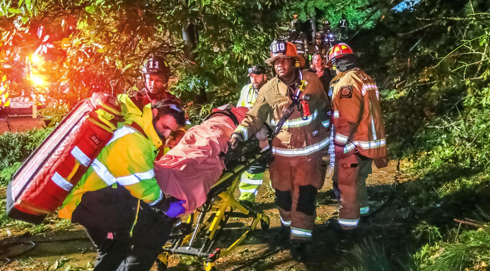 Atlanta firefighters transport a man they freed who was trapped in his third-floor bedroom after a tree came crashing down on a home on Brookview Drive in Atlanta, as Tropical Storm Zeta sped across the Southeast Thursday, Oct. 29, 2020. (John Spink/Atlanta Journal-Constitution via AP)