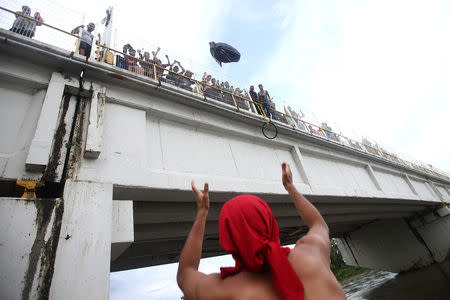 A Honduran migrant, part of a caravan trying to reach the U.S., throws a backpack from the bridge that connects Mexico and Guatemala to avoid the border checkpoint in Ciudad Hidalgo, Mexico, October 19, 2018. REUTERS/Edgard Garrido