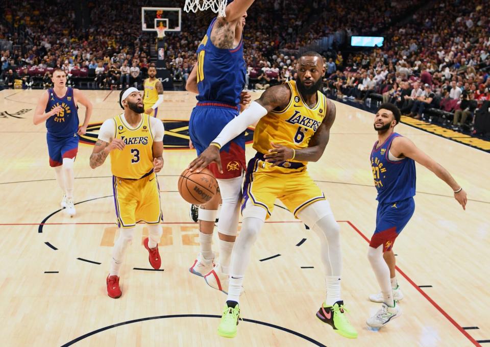 Lakers forward LeBron James wraps a pass around Nuggets forward Aaron Gordon to teammate Anthony Davis on the fast break.