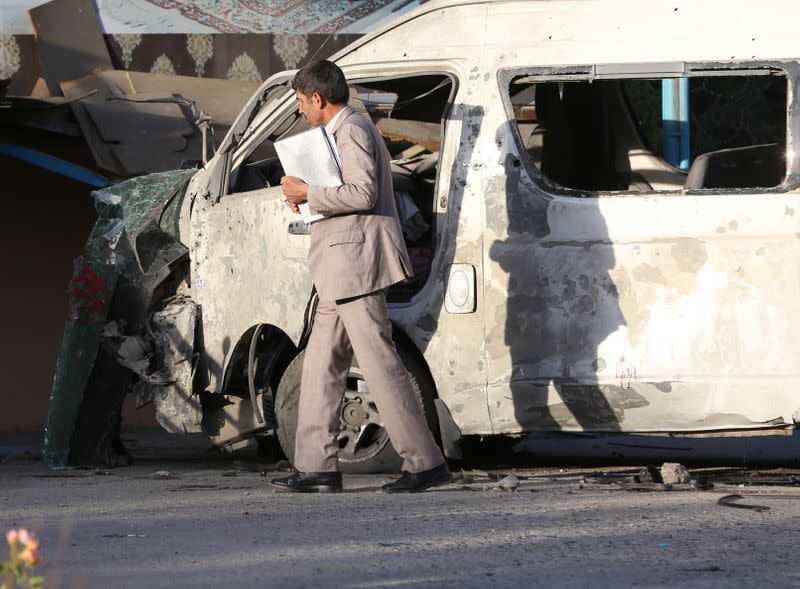 An Afghan official inspects the wreckage of a bus which carried employees of an Afghan television station and was bombed, in Kabul