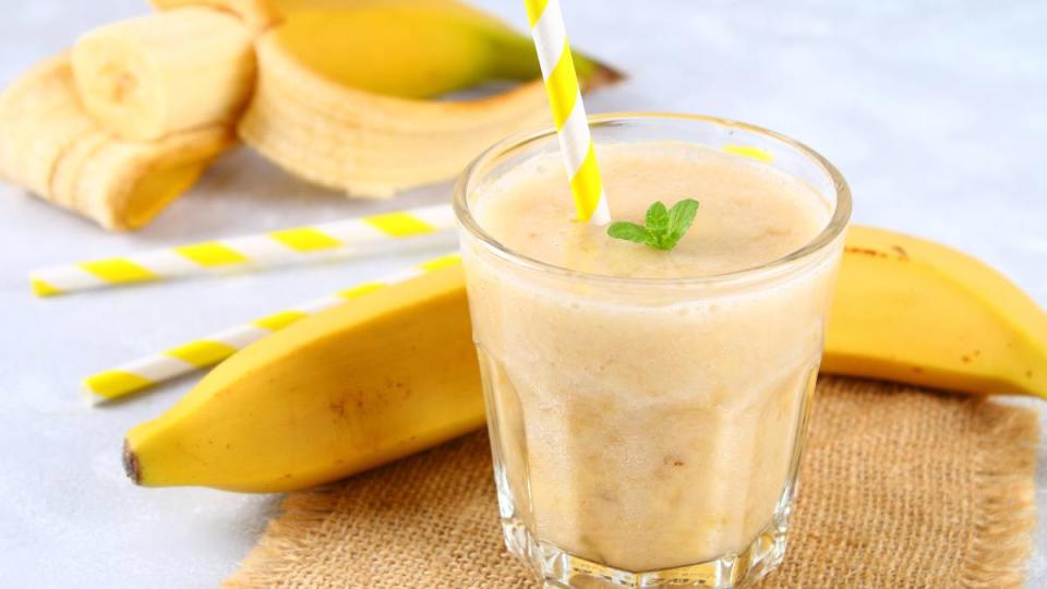 Slow Walk: Banana smoothie with a paper tube and mint. Bananas are whole and cut on a gray background