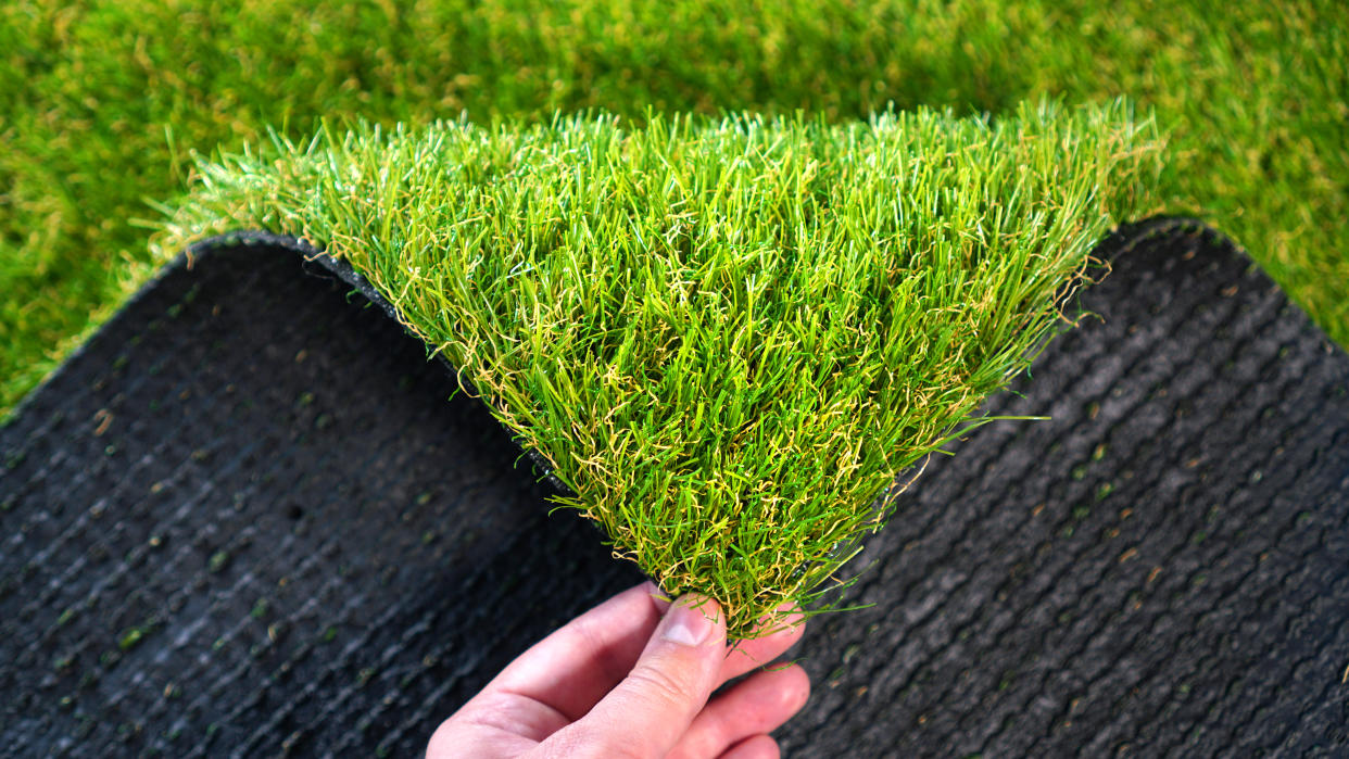 Hand holding an artificial grass roll. Greenering with an artificial turf.