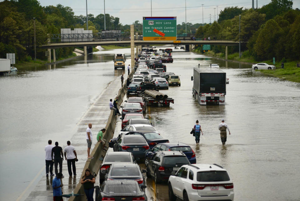 People wait outside of their stranded vehicles along Interstate 10 westbound at T.C Jester, Thursday, Sept. 19, 2019. The freeway is closed because of high water east bound on the freeway. (Mark Mulligan/Houston Chronicle via AP)