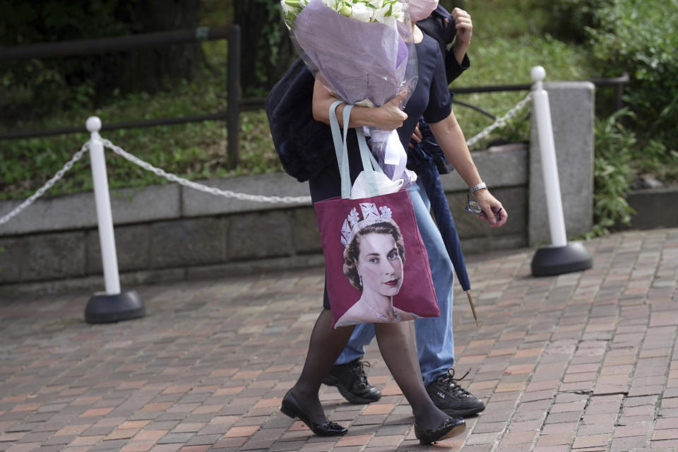 A mourner with flowers carries a bag featuring an image of Queen Elizabeth II near the British Embassy, Sept. 9, 2022, in Tokyo. (AP Photo/Eugene Hoshiko)