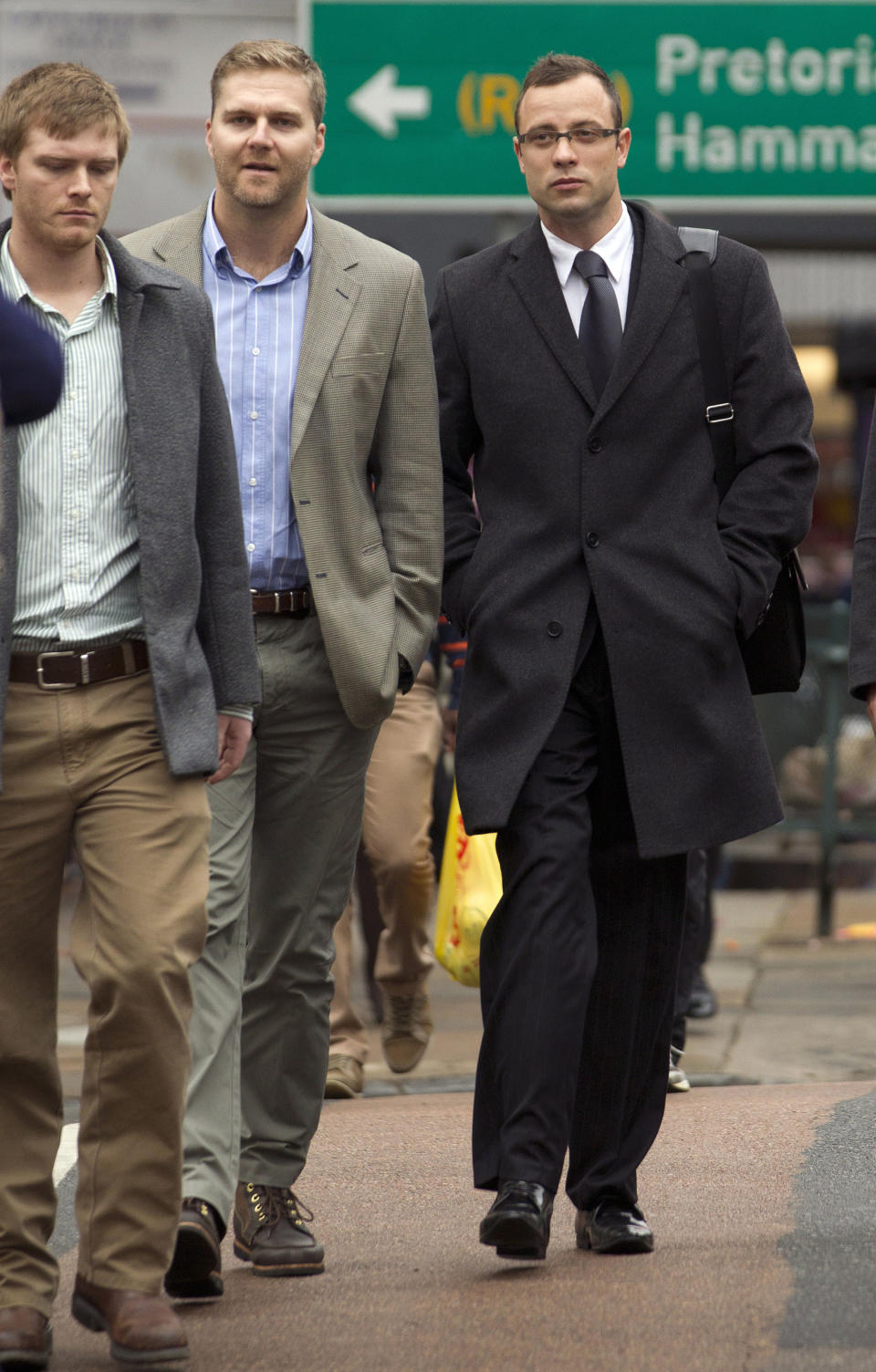 Oscar Pistorius, right, accompanied by unidentified men arrives at the high court for his trial in Pretoria, South Africa, Tuesday, March 11, 2014. Pistorius is charged with murder for the shooting death of his girlfriend, Reeva Steenkamp, on Valentines Day in 2013. (AP Photo/Themba Hadebe)