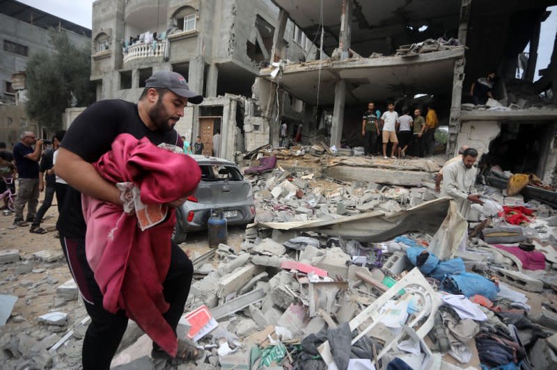 A Palestinian man carries the remains of a body, amidst destruction in the aftermath of Israeli bombing on a home in Rafah in the southern Gaza Strip on Sunday. Photo by Ismael Mohamad/UPI