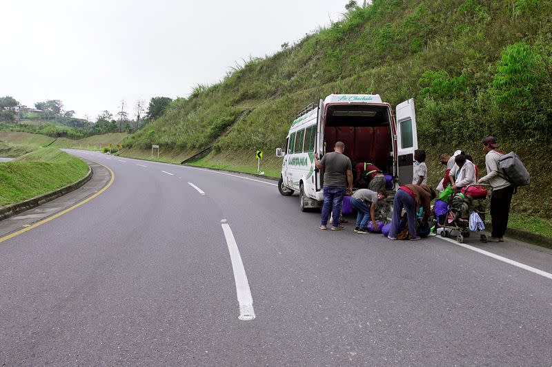 Venezuelan migrants load their belongings on a public service bus on a Colombian highway in Bucaramanga