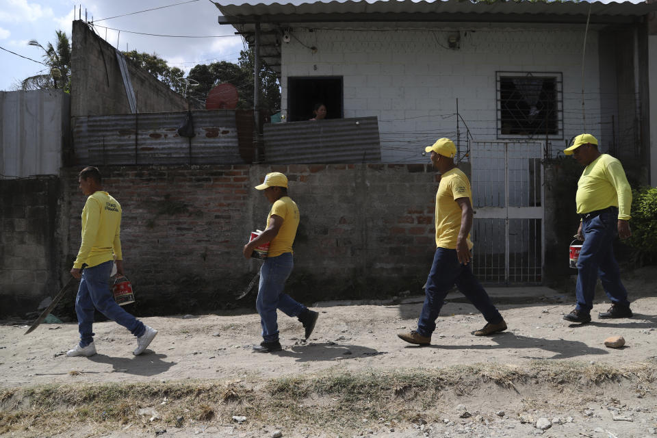 Prisoners walk with paint to be used to erase gang-related graffiti in Soyapango, El Salvador, Tuesday, Feb. 28, 2023. Erasing Such graffiti is part of the government's efforts to erase any trace of the gangs. (AP Photo/Salvador Melendez)