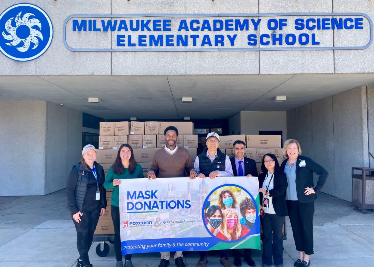 Officials from Foxconn Technology Group, Advocate Aurora and Milwaukee Academy of Science pose with a sign in front of boxes of medical masks. Foxconn donated 50,000 masks to the school and plans to donate a total of 2 million to 40 different charity groups.