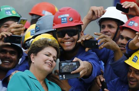 Brazil's President Dilma Rousseff poses for a "selfie" with workers during a visit to the Rio 2016 Olympic Park in Rio de Janeiro, in this file picture taken September 30, 2014. REUTERS/Ricardo Moraes/Files