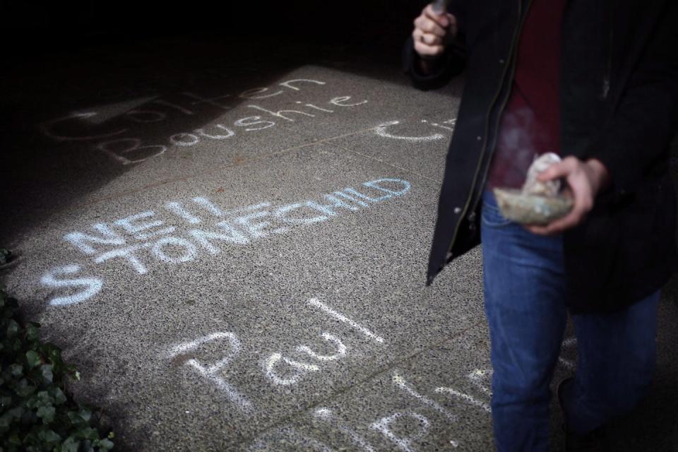 A man cleanses the area with sage as the names of Indigenous people victimized by the criminal justice system are written on a sidewalk during a protest in Victoria, B.C., in March 2018. THE CANADIAN PRESS/Chad Hipolito