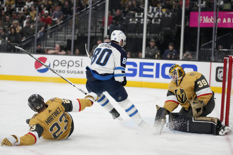 Vegas Golden Knights goaltender Laurent Brossoit (39) blocks a shot by Winnipeg Jets left wing Pierre-Luc Dubois (80) during the first period of Game 1 of an NHL hockey Stanley Cup first-round playoff series Tuesday, April 18, 2023, in Las Vegas. (AP Photo/John Locher)