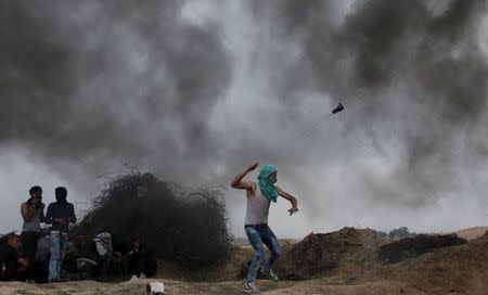 A Palestinian protester uses a sling to hurl stones at Israeli troops during clashes near border between Israel and Central Gaza Strip November 6, 2015. REUTERS/Ibraheem Abu Mustafa