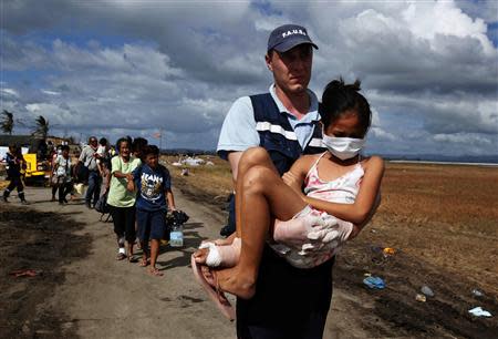 A volunteer from a French rescue team carries an injured girl to a military plane during an evacuation at Tacloban airport in the Typhoon Haiyan devastated city of Tacloban November 16, 2013. Survivors began rebuilding homes destroyed by Haiyan, one of the world's most powerful typhoons, and emergency supplies flowed into ravaged Philippine islands, as the United Nations more than doubled its estimate of people made homeless to nearly two million. REUTERS/Bobby Yip