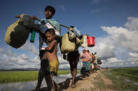 <p>Thousands of Rohingya refugees fleeing from Myanmar walk along a muddy rice field after crossing the border in Palang Khali, Cox’s Bazar, Bangladesh, on October 9, 2017. (Photograph by Paula Bronstein/Getty Images) </p>