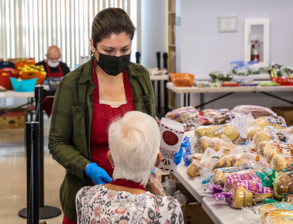 Community outreach coordinator Laura Gutierrez talks with a volunteer at the Cathedral City Senior Center food bank in Cathedral City, Calif., Monday, April 25, 2022. 