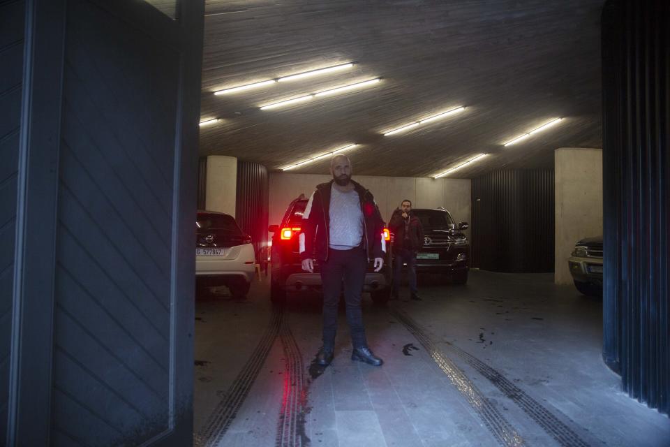 Men stand guard next to a vehicle as it arrives in the car park at the home of former Nissan Chairman Carlos Ghosn in Beirut, Lebanon, Thursday, Jan. 2, 2020. Turkish authorities have detained seven people as part of an investigation into how Ghosn, who skipped bail in Japan, was able to flee to Lebanon via Istanbul, Turkish media reported Thursday. (AP Photo/Maya Alleruzzo)