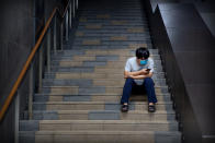 A man wearing a face mask to protect against the new coronavirus uses his smartphone as he sits on steps at an outdoor shopping mall in Beijing, Saturday, July 4, 2020. China reported a single new case of coronavirus in Beijing on Saturday, plus a few more cases elsewhere believed to have come from abroad. (AP Photo/Mark Schiefelbein)