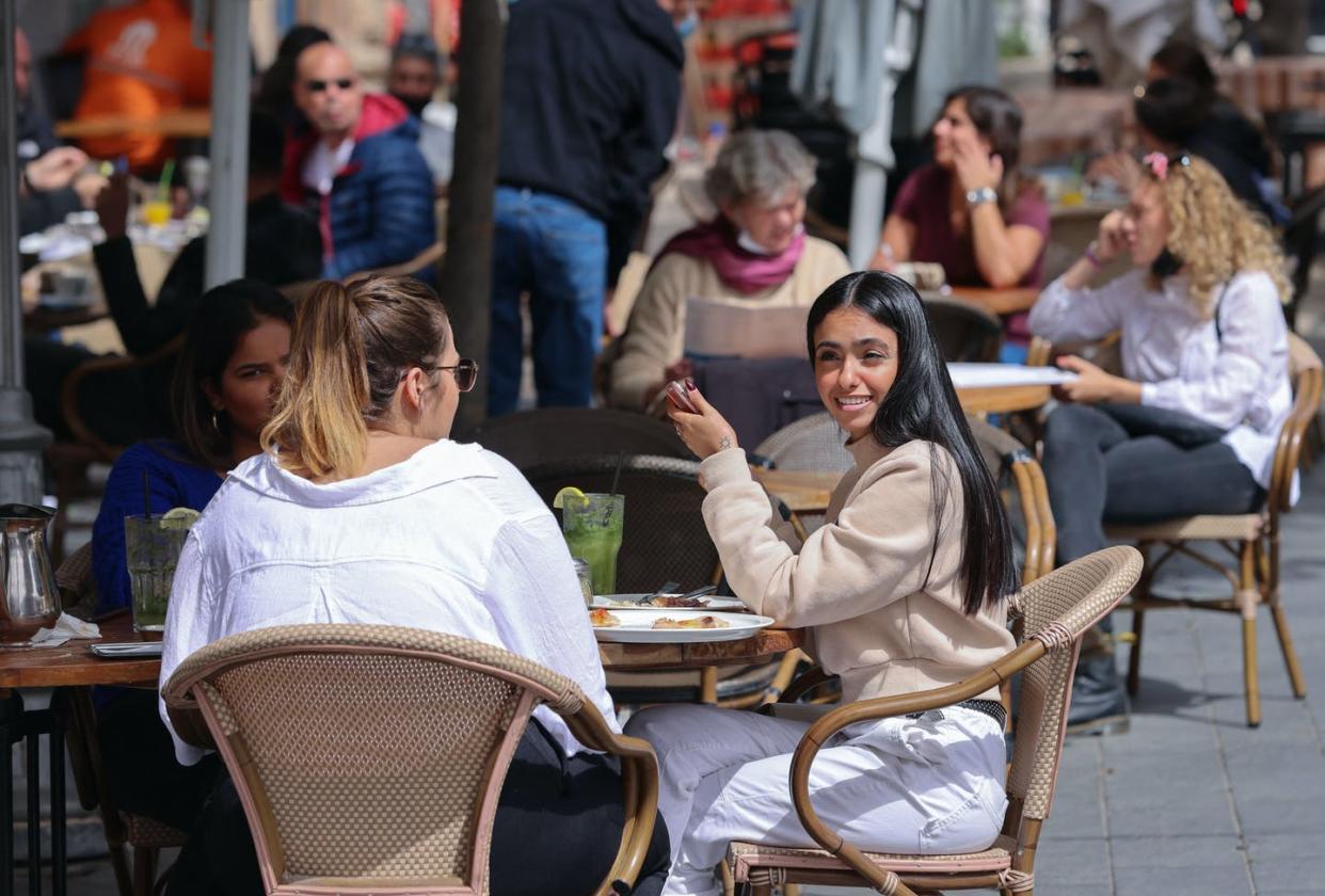 <span class="caption">Israeli diners with a 'green pass' get to enjoy a meal with friends</span> <span class="attribution"><a class="link " href="https://www.gettyimages.com/detail/news-photo/people-sit-at-cafe-terraces-in-jerusalem-on-march-9-after-news-photo/1231612020?adppopup=true" rel="nofollow noopener" target="_blank" data-ylk="slk:Emmanuel Dunand/AFP via Getty Images;elm:context_link;itc:0;sec:content-canvas">Emmanuel Dunand/AFP via Getty Images</a></span>