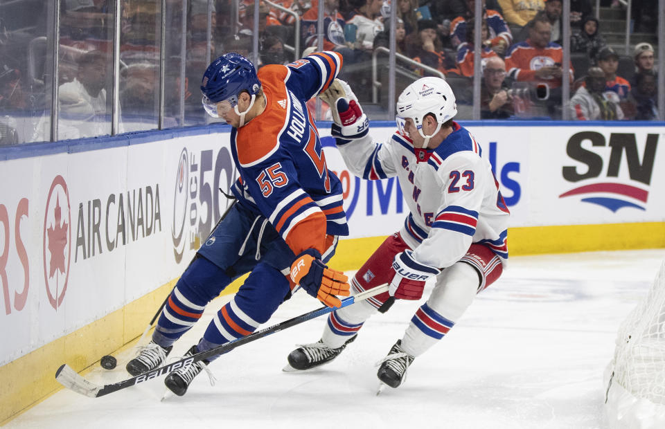 New York Rangers' Adam Fox (23) and Edmonton Oilers' Dylan Holloway (55) vie for the puck during the second period of an NHL hockey game Thursday, Oct. 26, 2023, in Edmonton, Alberta. (Jason Franson/The Canadian Press via AP)