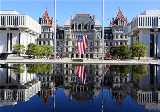 The state Capitol is reflected in a fountain before a ceremony at the New York State Fallen Firefighters Memorial on Tuesday, Oct. 6, 2015, in Albany, N.Y.