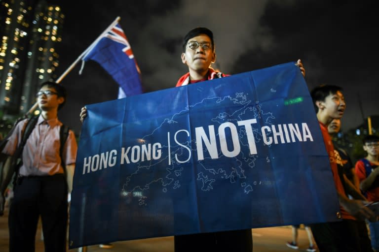 A football fan displays a banner reading "Hong Kong is not China" in front of another fan carrying the old British colonial flag (back L) after a match in Hong Kong