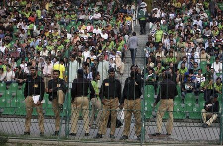 Pakistani policemen stand guard as spectators watch the first Twenty20 Cricket match between Pakistan and Zimbabwe in Lahore, Pakistan, May 22, 2015. Zimbabwe are the first test-playing nation to tour Pakistan since a 2009 terror attack on the Sri Lanka team bus in Lahore left the driver dead and several players injured. REUTERS/Mohsin Raza