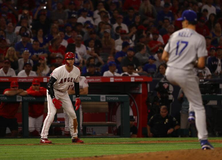 The Angels' Shohei Ohtani steps away from third base and watches Dodgers pitcher Joe Kelly deliver a throw