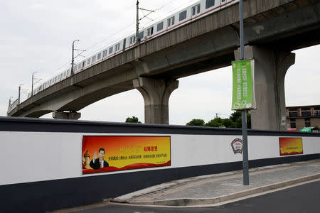 A poster with a portrait of Chinese President Xi Jinping is seen at a wall in Shanghai, China, September 29, 2017. The slogan reads: "The Four Comprehensives: Comprehensively build a moderately prosperous society. Comprehensively deepen reform. Comprehensively govern the nation according to law. Comprehensively strictly govern the Party." Picture taken September 29, 2017. REUTERS/Aly Song