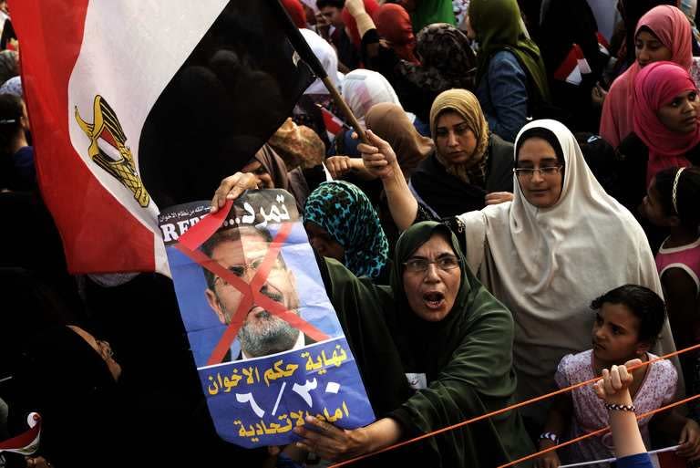 Opposition protesters shout slogans and show a defaced poster of their president outside the presidential palace on July 2, 2013 in Cairo. Egypt was on edge Wednesday after President Mohamed Morsi refused to quit hours before an army ultimatum expires, following deadly violence during rival mass protests in Egypt's worst crisis since its 2011 revolution