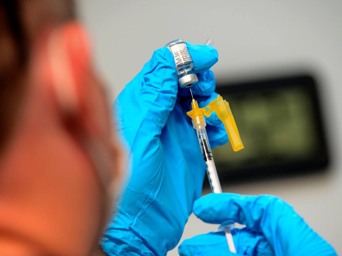 A health-care worker prepares a dose of Pfizer's bivalent COVID-19 vaccine. (Kristopher Radder/The Associated Press - image credit)