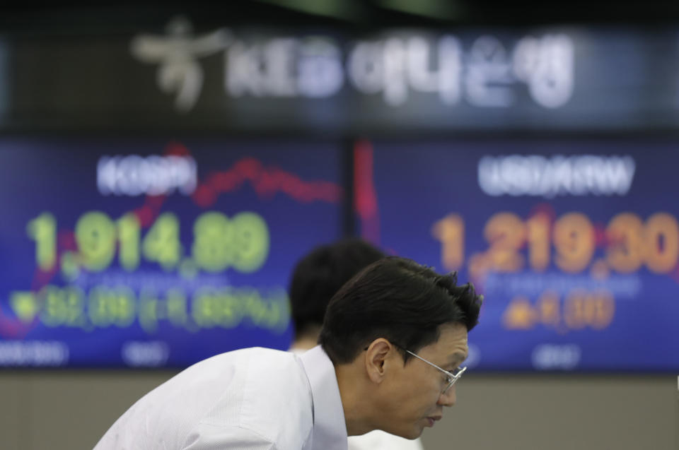 A currency trader watches the computer monitors near the screens showing the Korea Composite Stock Price Index (KOSPI), left, and the foreign exchange rate between U.S. dollar and South Korean won at the foreign exchange dealing room in Seoul, South Korea, Tuesday, Aug. 6, 2019. Asian stocks followed Wall Street lower on Tuesday after China let its currency sink and halted purchases of U.S. farm goods, fueling fears Beijing's trade war with President Donald Trump will harm the global economy. (AP Photo/Lee Jin-man)