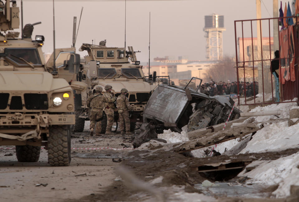 FILE - U.S. soldiers and Afghan security forces search the site where a suicide attacker rammed a car bomb into a NATO convoy killing two foreign civilian contractors, in the Afghan capital Kabul, Afghanistan, Feb. 10, 2014. At a time when Americans are deeply divided along party lines, a new poll shows agreement on at least one issue: the United.States' two-decade long war in Afghanistan was not worth fighting. (AP Photo/Rahmat Gul, File)