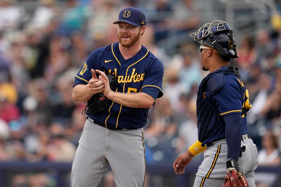 Milwaukee Brewers starting pitcher Brandon Woodruff, left, and catcher William Contreras talk after a solo home run by Seattle Mariners' Cooper Hummel during the third inning of a spring training baseball game, Monday, March 20, 2023, in Peoria, Ariz. (AP Photo/Abbie Parr)