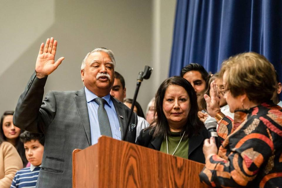 Whatcom County Executive Satpal Sidhu, left, takes the oath of office from Whatcom County Auditor Debbie Adelstein, right, as Sidhu’s wife Mundir Sidhu watches on Jan. 11, 2020, at Meridian High School.