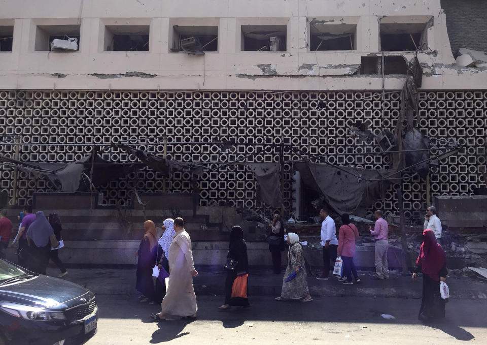 People survey the aftermath of a fiery car crash outside the National Cancer Institute in Cairo, Egypt, Monday, Aug. 5, 2019. The multiple-car crash set off an explosion that ignited a fire at Egypt's main cancer hospital, the government said.(AP Photo/Maya Alleruzzo)