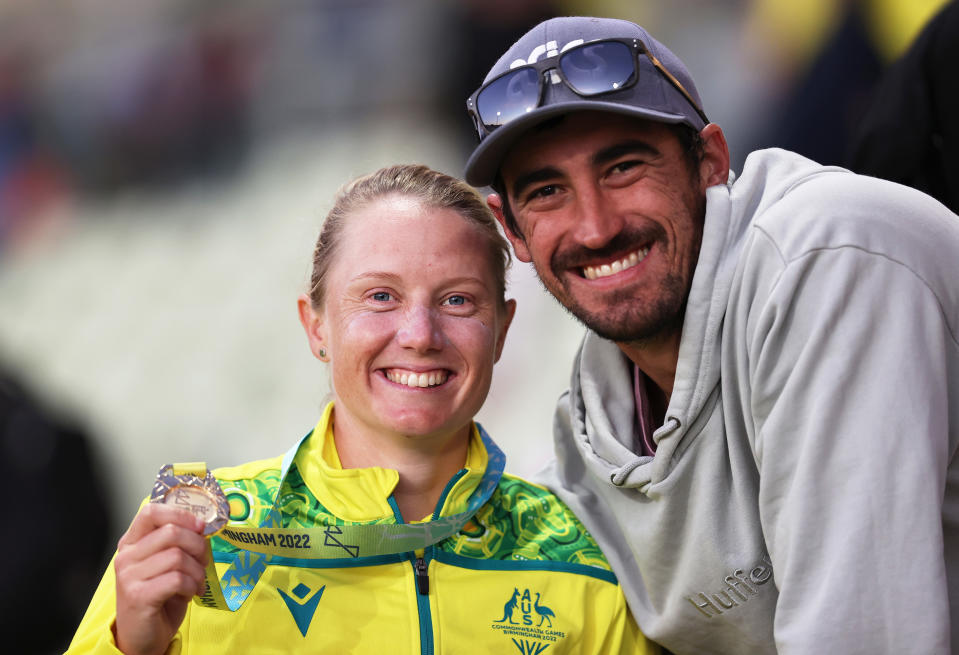 BIRMINGHAM, ENGLAND - AUGUST 07: Alyssa Healy of Team Australia poses alongside Mitchell Starc after being presented with a Gold Medal during the Cricket T20 - Gold Medal match between Team Australia and Team India on day ten of the Birmingham 2022 Commonwealth Games at Edgbaston on August 07, 2022 on the Birmingham, England.  (Photo by Ryan Pierse/Getty Images)