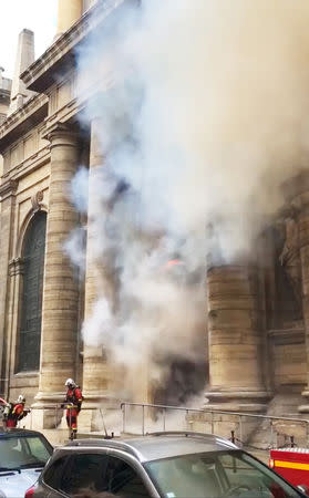 Members of the fire brigade react as a smoke rises from Saint-Sulpice church in Paris, France, March 17, 2019 in this still image taken from a social media video obtained on March 18, 2019. INSTAGRAM @agneswebste/via REUTERS