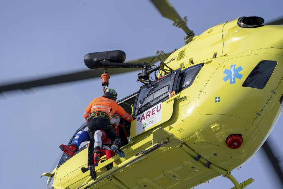 Austria's Marco Schwarz, partially seen at left, is airlifted after crashing during an alpine ski, men's World Cup downhill race, in Bormio, Italy, Thursday, Dec. 28, 2023. Schwarz appeared to hurt his right knee in a left turn before getting thrown off the course halfway through his run. He was taken off the hill by a helicopter. (AP Photo/Giovanni Zenoni)