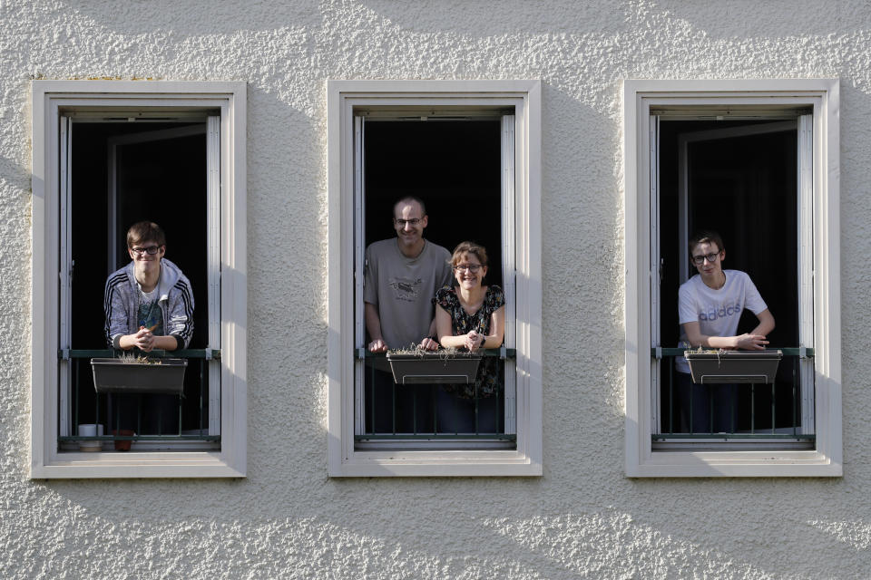 In this photo taken Thursday, April 16, 2020, Jerome, second left, Nadege and their children Thomas, 17, left and Pierre, 14, both with intellectual disabilities pose at the window of their apartment in Montigny-le-Bretonneux, near Paris. Coronavirus lockdown is proving an ordeal for kids with disabilities and their families who are having to care for them at home because special schools have been shut down to curb infections. The family requested to be identified by their first name out of concern for privacy. (AP Photo/Christophe Ena)