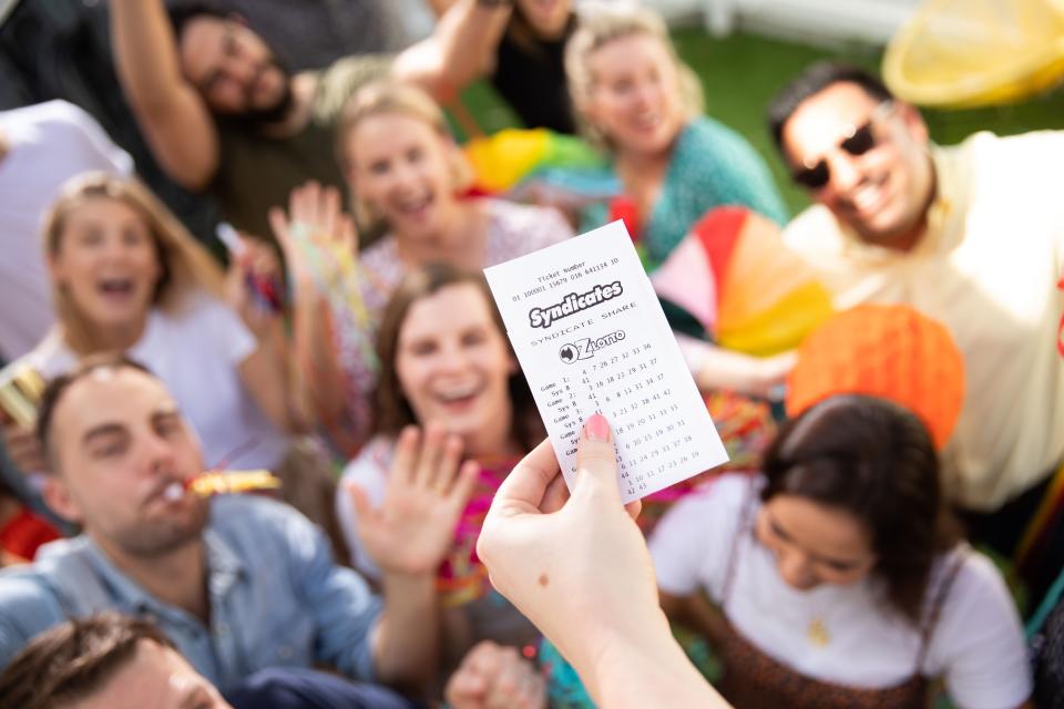 Stock image of people celebrating in front of a Lotto ticket.