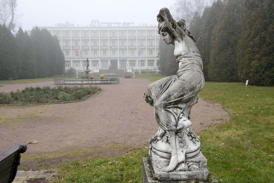 A spa sanatorium view with a stature in the foreground in Morshyn, Ukraine, Wednesday, Nov. 17, 2021. In Morshyn, a scenic town nestled at the Carparthian foothills in the Lviv region, 74% of 3,439 residents have been fully vaccinated. A small spa town in western Ukraine stands out in a country where just under a quarter of the population has received coronavirus vaccines. (AP Photo/Efrem Lukatsky)