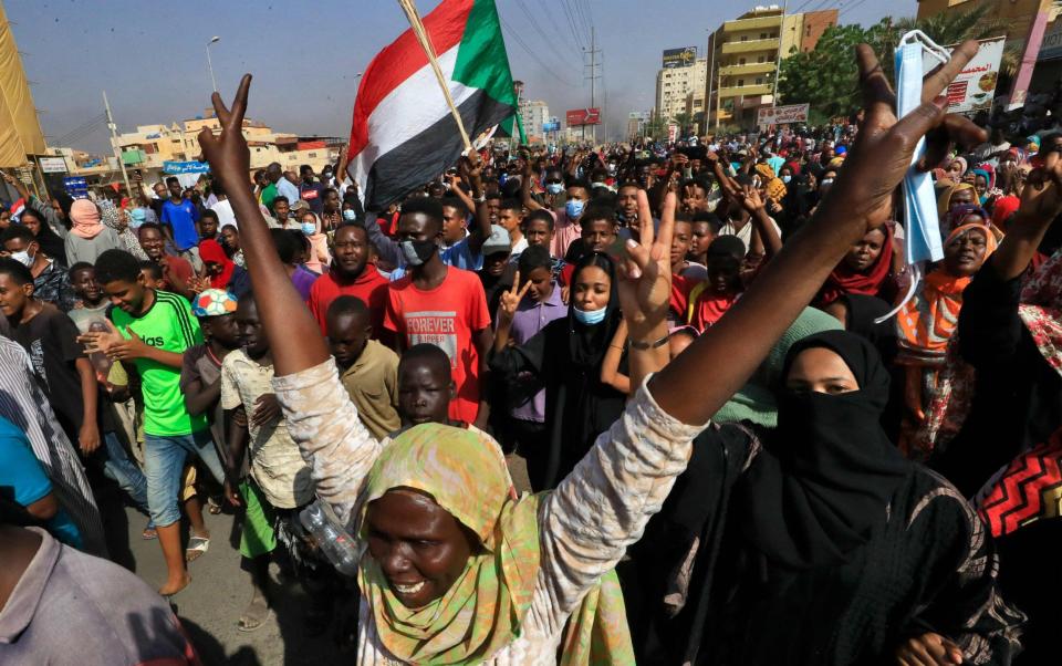 Sudanese protesters lift national flags as they rally to denounce the detentions - AFP