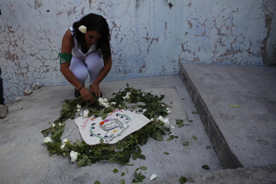 An activist from the "Women from the Periphery for the Periphery Collective" places flowers where the body of 2-year-old Samantha was found dead outside her home in June, during a caravan to protest femicide in Ecatepec, Mexico, Sunday, Oct. 6, 2019. The collective of activists and the relatives of murdered females visited four sites where females were found dead in Ecatepec, in the state of Mexico where authorities declared in 2015 an alert concerning gender violence against women. (AP Photo/Ginnette Riquelme)